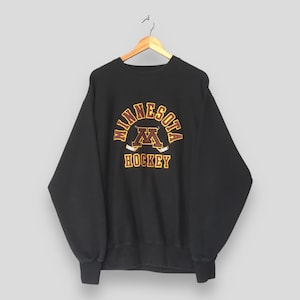 May include: Black crew neck sweatshirt with "Minnesota Hockey" text in gold and maroon. The sweatshirt has a vintage design with the letter "M" and crossed hockey sticks.