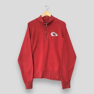 Op de afbeelding: Een rood sweatshirt met lange mouwen en een korte rits, voorzien van een wit en rood Kansas City Chiefs pijlpuntsymbool geborduurd op de linkerborst. Het kledingstuk heeft een hoge kraag en geribbelde boorden aan mouwen en zoom.