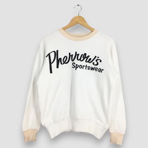 Może przedstawiać: Biała bluza z długim rękawem z czarnym logo "Pherrrow's Sportswear".