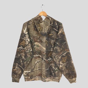 May include: A hooded sweatshirt with a camouflage pattern. The design features a blend of brown, green, and tan hues, mimicking a forest environment. The sweatshirt has a front pocket and a drawstring hood, suitable for outdoor activities.