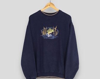 May include: Navy blue sweatshirt with a detailed embroidered design of a fish jumping out of water, surrounded by reeds. The sweatshirt has a crew neck with a tan trim and ribbed cuffs and hem. The design is in shades of green, blue, and tan.