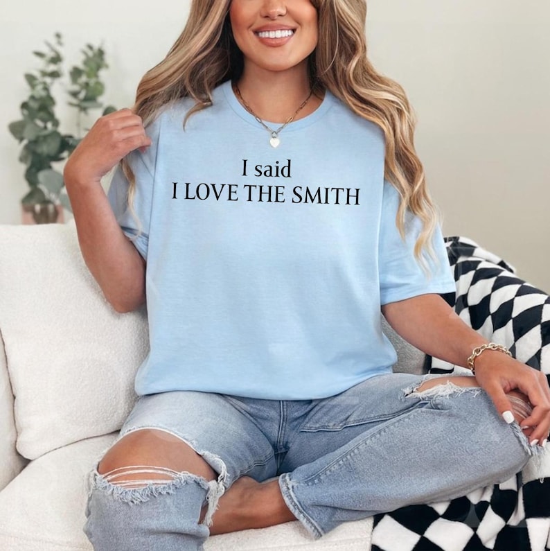 May include: A light blue t-shirt with the text "I said I LOVE THE SMITH" printed in black.