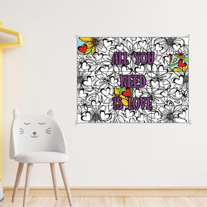 May include: A black and white floral print poster with the text "ALL YOU NEED IS LOVE" in purple. The poster has colorful accents of yellow, red, and blue. The poster is hanging on a white wall.