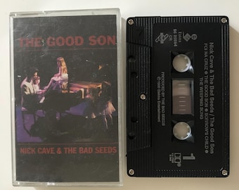 May include: A black cassette tape with a white label. The label has the title "The Good Son" and the artist "Nick Cave & The Bad Seeds". The cassette tape is in a plastic case.