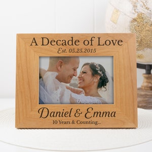 May include: A wooden picture frame with the text "A Decade of Love Est. 05.25.2015 Daniel & Emma 10 Years & Counting..."  A photo of a couple is in the frame.