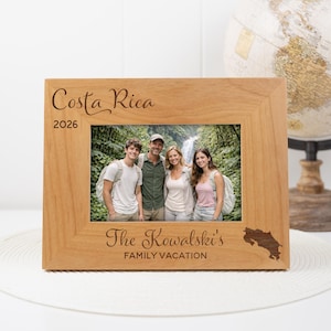 May include: A wooden photo frame with a family vacation photo from Costa Rica in 2026. The frame is engraved with "Costa Rica", "The Kowalski's FAMILY VACATION", and a Costa Rica outline. A globe is in the background.