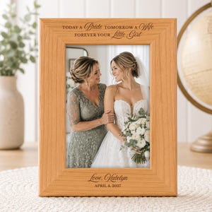 Puede incluir: Un marco de fotos de madera clara con el texto grabado "TODAY A Bride TOMORROW A Wife FOREVER YOUR Little Girl" en la parte superior y "Love, Katelyn APRIL 4, 2027" en la parte inferior, mostrando una foto de dos personas.
