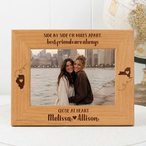 May include: A rectangular light brown wooden picture frame featuring the engraved text "SIDE BY SIDE OR MILES APART, best friends are always" at the top and "CLOSE AT HEART Melissa ♥ Allison" at the bottom, with state outlines on the sides.