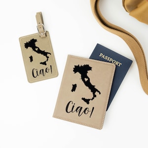 May include: Tan leather passport holder and luggage tag with a black outline of Italy and the word "Ciao!" printed on each. The luggage tag has a silver buckle.