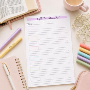 May include: A white Bible Translation Sheet with a purple header, featuring a line for a verse and six colored rectangular boxes with corresponding lined sections for notes. The paper is surrounded by a notebook, pens, and a coffee mug.