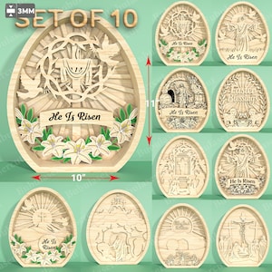 Op de afbeelding: Set van 10 houten paasei-decoraties. Het hoofdei is 25.4 cm breed en 27.9 cm hoog, met de tekst "He Is Risen" en een bloemenontwerp. Andere eieren tonen religieuze scènes.