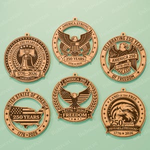 K&ouml;nnte beinhalten: Sechs Holzornamente mit patriotischen Designs. Jedes Ornament zeigt den Text "250 Jahre" und "1776-2026" sowie Bilder eines Adlers, der Freiheitsglocke und der amerikanischen Flagge. Die Ornamente sind lasergeschnitten.