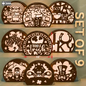 Puede incluir: Un conjunto de nueve decoraciones de madera para el Día de San Patricio. Cada pieza es un semicírculo con intrincados diseños recortados, incluyendo tréboles, jarras de cerveza y duendes. Una pieza dice "100% Irish" y otra mide 25,4 cm de ancho.