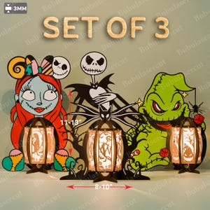May include: Set of 3 Halloween-themed wooden lanterns with character cutouts, including Jack Skellington, Sally, and Oogie Boogie. The lanterns are 8-10 inches wide and 11-13 inches tall. The text "SET OF 3" is displayed at the top.