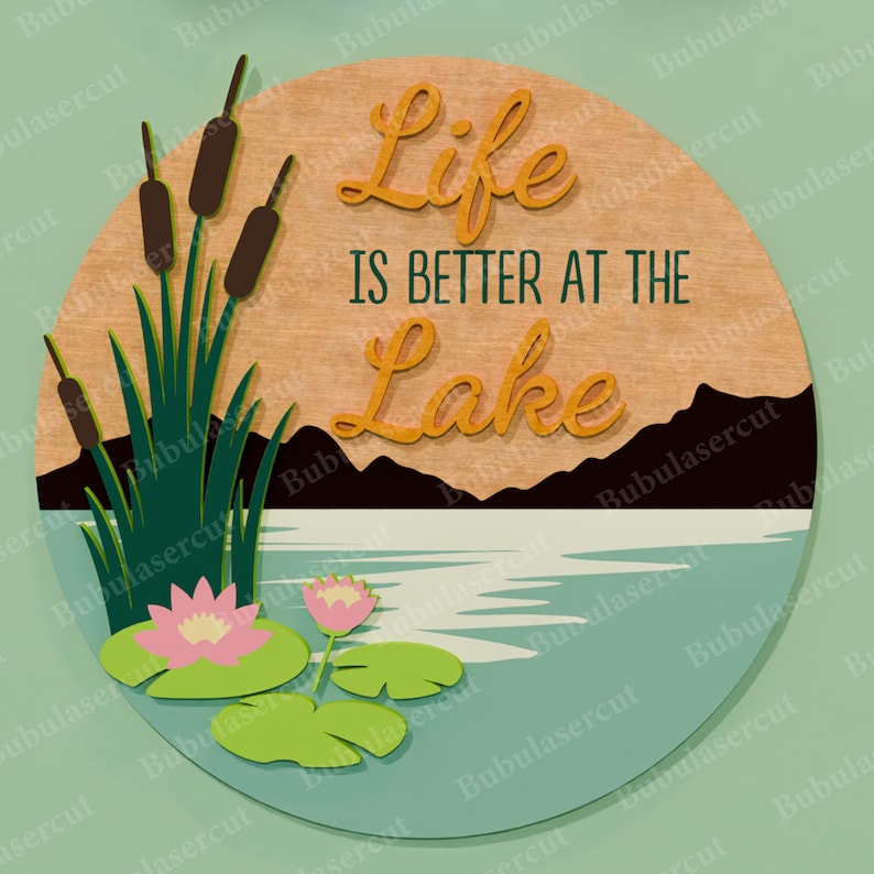 May include: A round wooden sign with the text "Life is Better at the Lake". The sign features a lake scene with cattails, water lilies, and mountains. The text is in a script font.