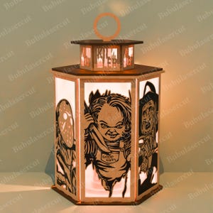 May include: A wooden, hexagonal lantern with a handle, featuring cut-out images of horror movie characters. The lantern has a light inside, illuminating the characters. The top of the lantern reads "KILLER".