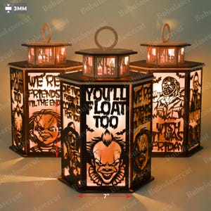 May include: Three Halloween-themed lanterns with laser-cut designs. Each lantern features a hexagonal shape with a wooden frame and a handle. The designs include horror movie characters and phrases like "You'll Float Too." The lanterns are approximately 7 inches wide.