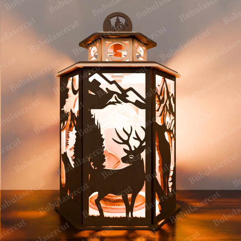May include: A wooden lantern featuring a cut-out design of a deer standing in a forest scene. The lantern is lit from within, casting a warm glow.