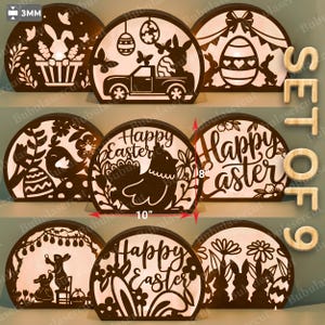 Könnte beinhalten: Set aus 9 lasergeschnittenen Osterdekorationen aus Holz. Jedes halbkreisförmige Stück zeigt komplizierte Designs von Hasen, Eiern und dem Text "Happy Easter". Das größte Stück ist 25,4 cm breit und 20,3 cm hoch.