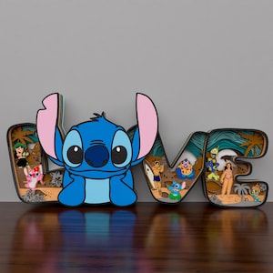 May include: A wooden cutout of the word 'LOVE' with a blue Stitch character in the center of the 'O'. The 'L' and 'V' are decorated with palm trees and ocean waves. The 'E' has a surfboard and a Stitch character wearing a lei. The cutout is on a wooden surface.