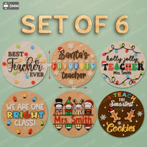 Puede incluir: Un conjunto de seis letreros de madera para agradecer a los profesores, cada uno de 30 cm de diámetro. Los letreros presentan diseños festivos con frases como "Best Teacher Ever" y "Holly Jolly Teacher". Se incluyen acentos coloridos y texto.