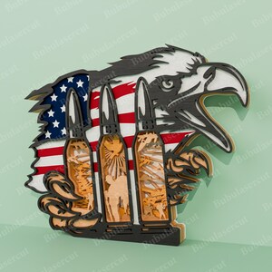Pu&ograve; includere: Un'incisione in legno di un'aquila con le ali spiegate, che tiene tre proiettili negli artigli. L'aquila &egrave; appollaiata su una bandiera americana. I proiettili sono finemente disegnati con scene di soldati e attrezzature militari.