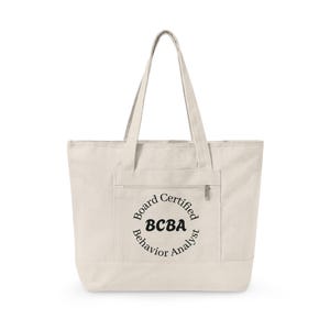 May include: Cream-coloured tote bag with a front pocket and zip closure. The bag features a circular design with the text "Board Certified BCBA Behavior Analyst" in black. The tote has two long handles for carrying.
