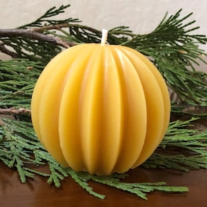 May include: A round, yellow, honeycomb-textured beeswax candle.