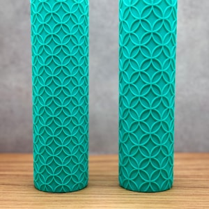 May include: Two teal blue silicone rolling pins with a geometric pattern. The rolling pins are cylindrical and have a textured surface.
