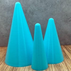 May include: Three turquoise blue cone-shaped ceramic display stands of varying sizes. The largest cone is in the back, the smallest cone is in the front, and the medium-sized cone is in the middle.