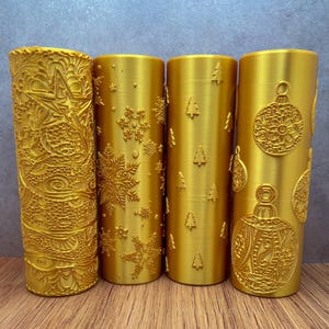 Puede incluir: Cuatro rodillos de amasar de color dorado con diferentes diseños navideños en relieve. Los diseños incluyen copos de nieve, árboles de Navidad y adornos.