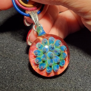 Hand blown glass implosion pendant, handmade borosilicate glass necklace, with sparkly blue/green flower and twisted sterling bail