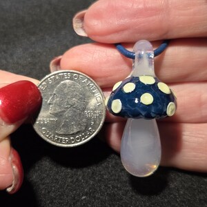 Pendant size compared to a quarter and it is larger measuring 1.6 inches long with the glass bail.  The round portion measures .85 inches diameter.