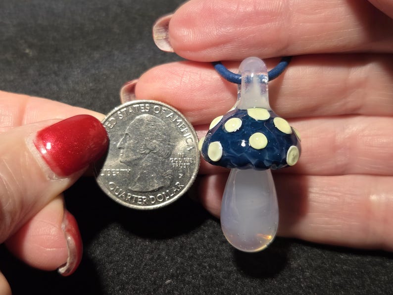 Pendant size compared to a quarter and it is larger measuring 1.6 inches long with the glass bail.  The round portion measures .85 inches diameter.