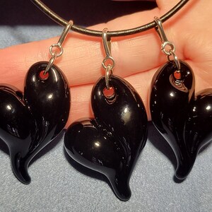 Three black glass heart shaped pendants on a black leather cord necklace.