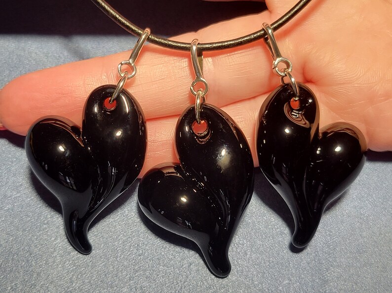 Three black glass heart shaped pendants on a black leather cord necklace.