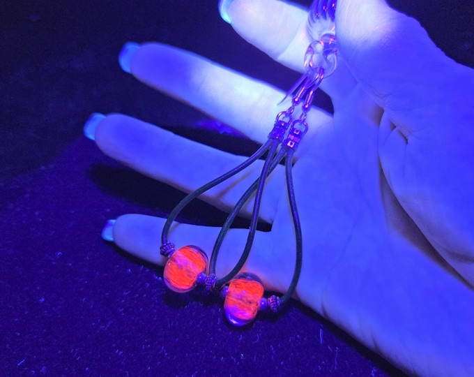 Whimsical earrings with UV reactive glow glass, sterling silver and round black leather.  Handmade lampwork bead earrings.