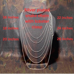 Display bust showing multiple silver-plated snake chains layered by length, labeled from 16 to 26 inches, each with a lobster clasp, demonstrating available necklace length options on a dark textured background.
