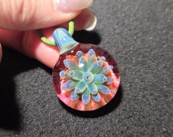Hand blown glass implosion pendant, handmade borosilicate glass necklace, with sparkly blue/green flower.