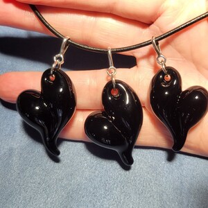 Three black glass heart shaped pendants on a black leather cord necklace.
