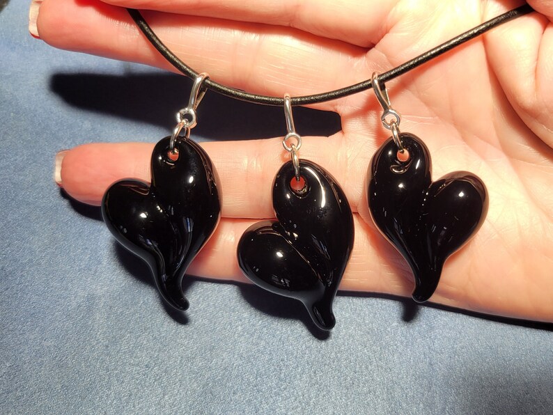 Three black glass heart shaped pendants on a black leather cord necklace.