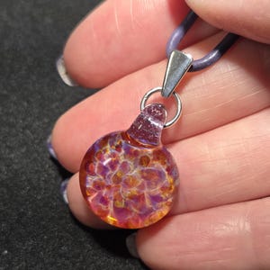 Handcrafted art glass necklace featuring a tiny autumn choker pendant with vibrant trippy colors, reflecting light to highlight its unique depth and detail.