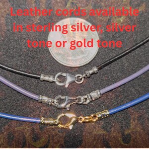 Close-up of leather necklace cords shown with 10mm large lobster claw clasps, displayed in sterling silver, silver tone, and gold tone finishes, with a U.S. quarter above for size reference on a dark textured background.
