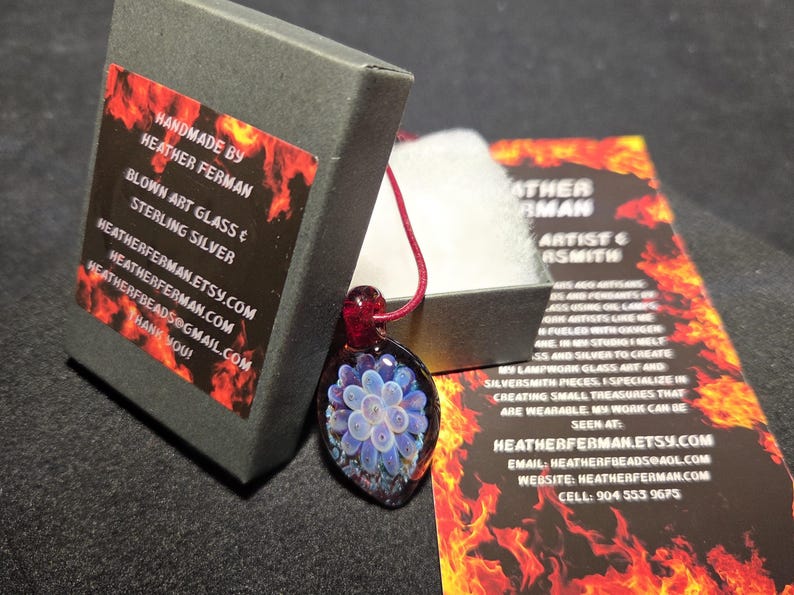 Image of the pendant and a jewelry box labeled with the business name. A business bookmark explains the glassmaking process, accompanying the pendant for a complete gift presentation.