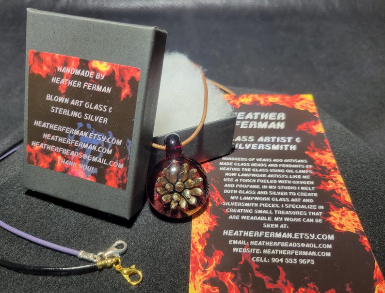 Image of the pendant and a jewelry box labeled with the business name. A business bookmark explains the glassmaking process, accompanying the pendant for a complete gift presentation.