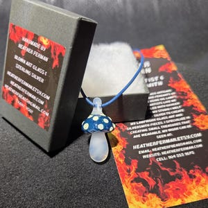 Image of the pendant and a jewelry box labeled with the business name. A business bookmark explains the glassmaking process, accompanying the pendant for a complete gift presentation.