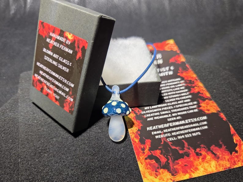 Image of the pendant and a jewelry box labeled with the business name. A business bookmark explains the glassmaking process, accompanying the pendant for a complete gift presentation.