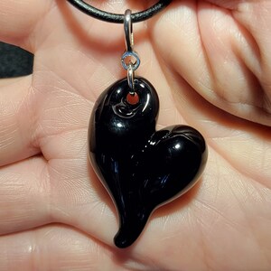 A black glass heart pendant on a black leather cord necklace.