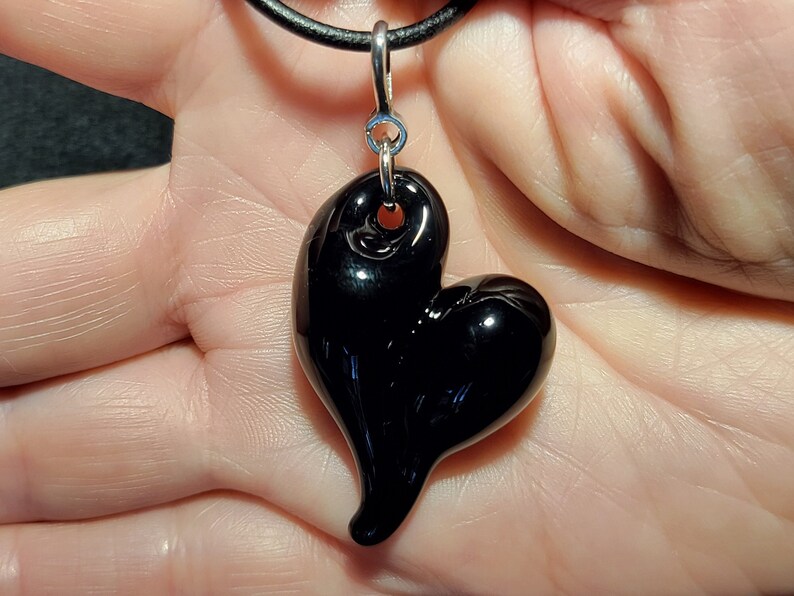A black glass heart pendant on a black leather cord necklace.