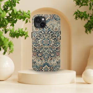 Peut inclure: Coque de téléphone ornée d'un motif floral détaillé dans des tons de bleu, beige et rose. L'étui présente une découpe pour l'appareil photo et un design protecteur, avec un motif symétrique complexe.